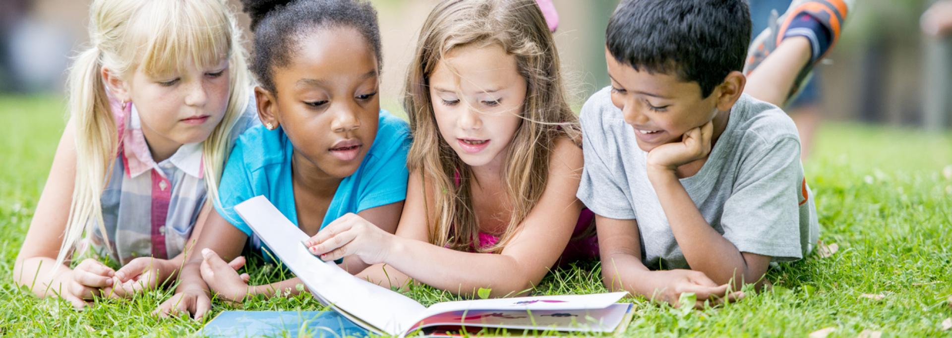 Des enfants en train de lire en extérieur