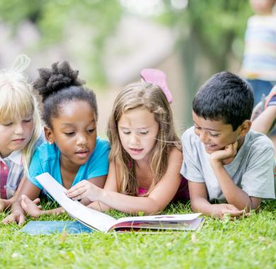 Des enfants en train de lire en extérieur