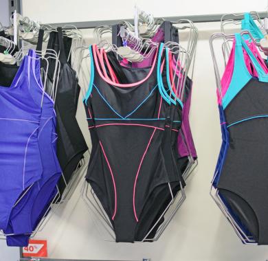 Maillots de bain noirs et violets féminins sur des cintres dans un magasin